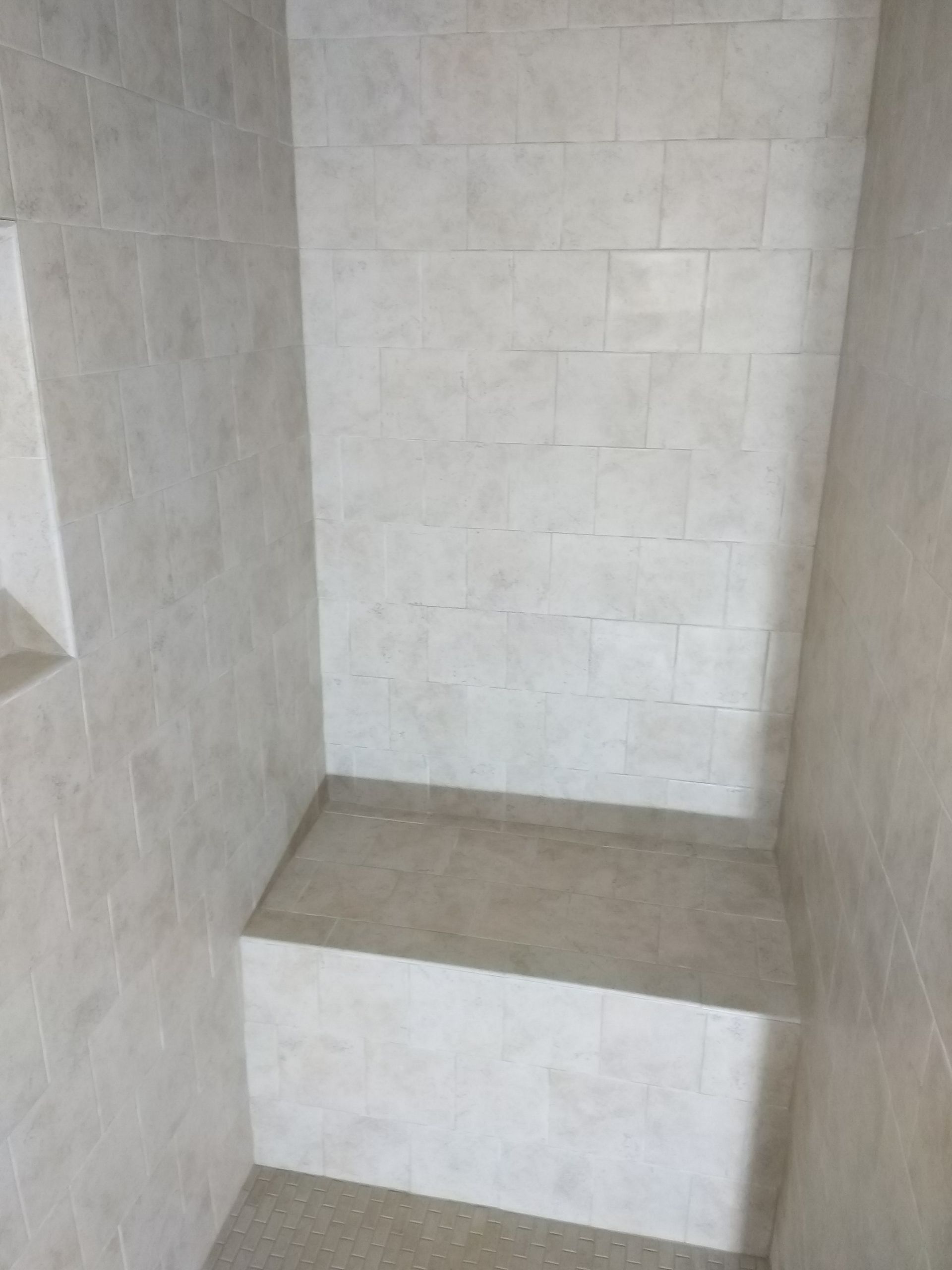 Empty tiled shower stall with a built-in bench or ledge.