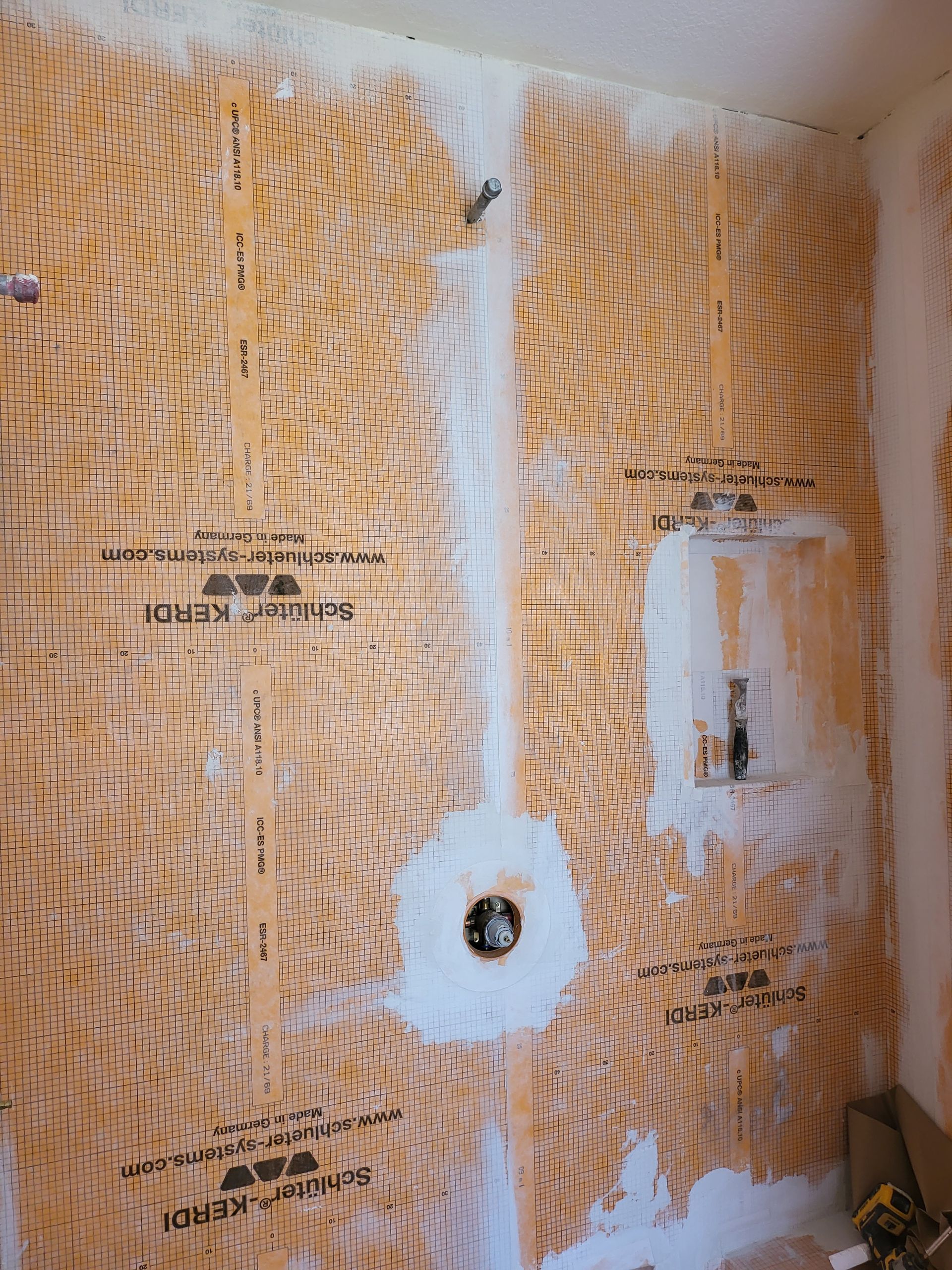 Damaged interior wall with exposed insulation, white patching compound, and a hole around a pipe opening