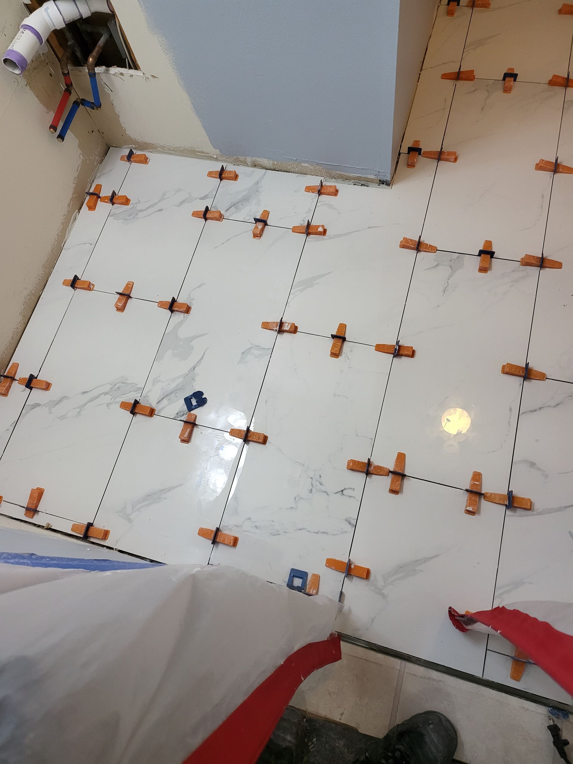 Tiled bathroom floor with scattered orange trim and white fixtures at the edges, viewed from above.