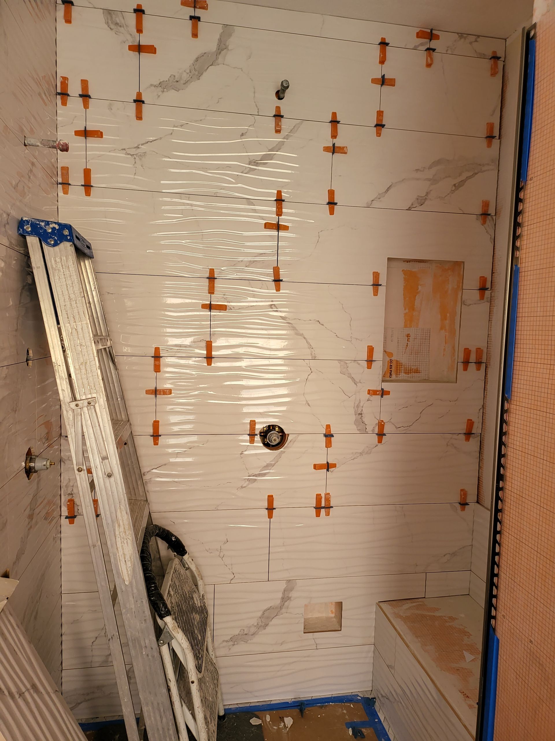 Bare unfinished room with wall anchors, leaning boards, and blue tape along the edges