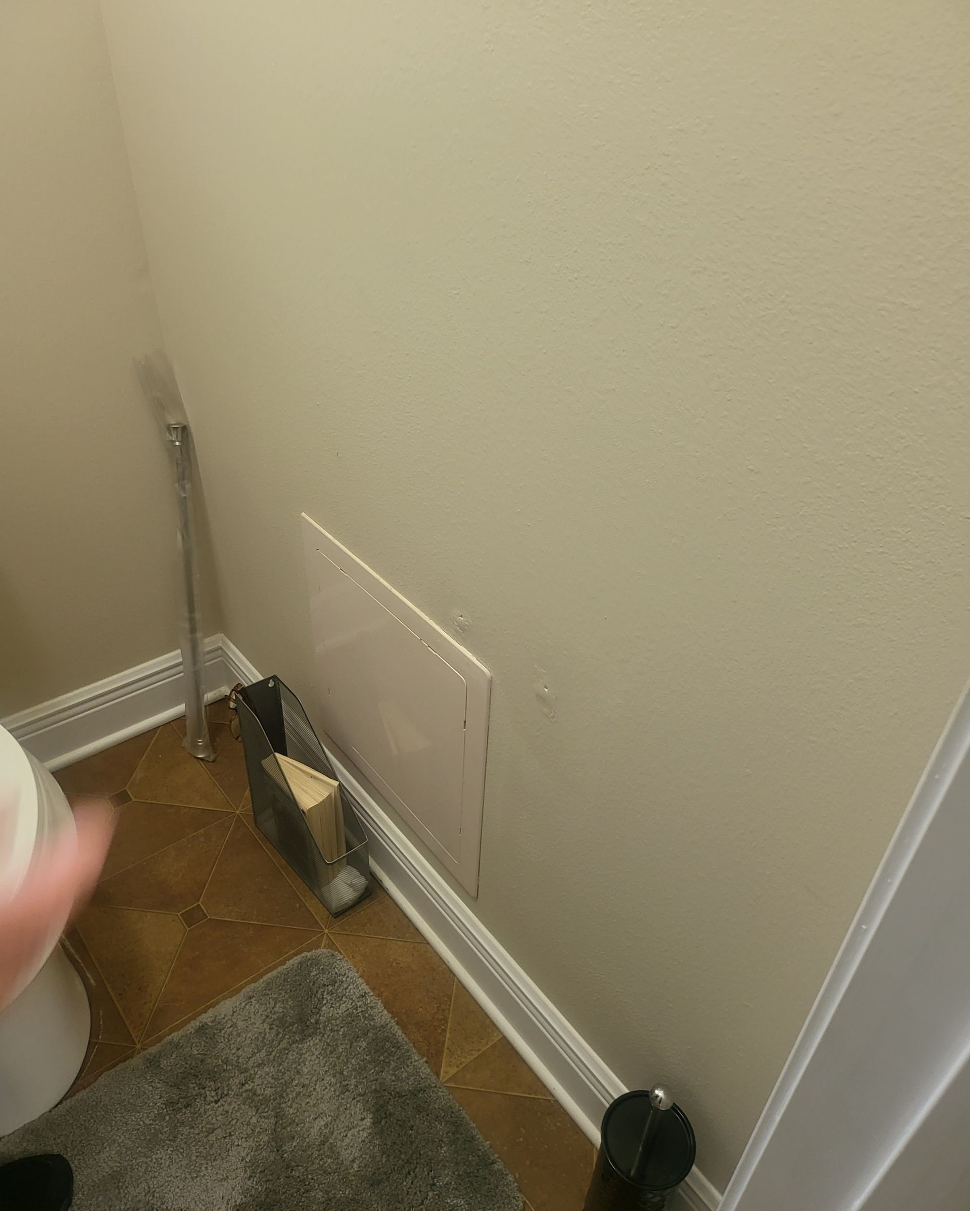 Home hallway corner with exposed wall panel, tools, and a gray rug on the floor