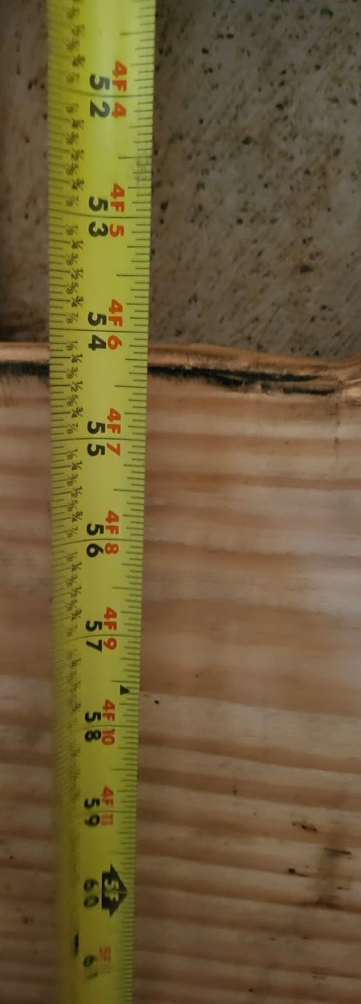 Yellow tape measure beside a wooden board, showing height markings.