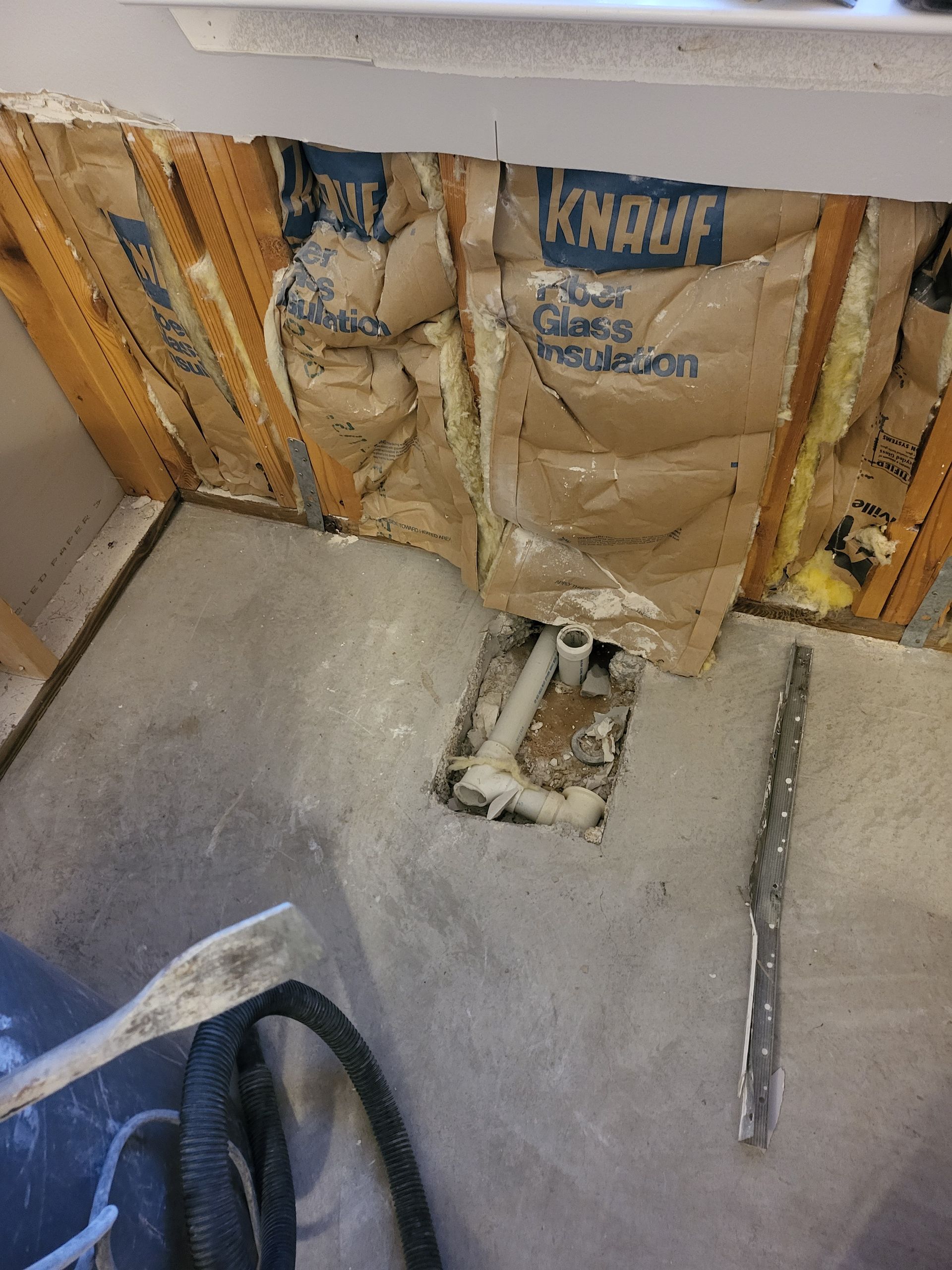 Insulated wall with exposed studs and floor plumbing in a construction or renovation area