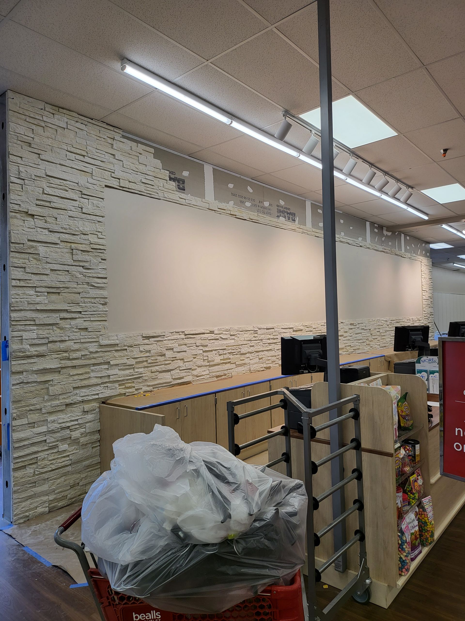 Store interior with empty wall display, shelves, and a trash bin in the foreground.