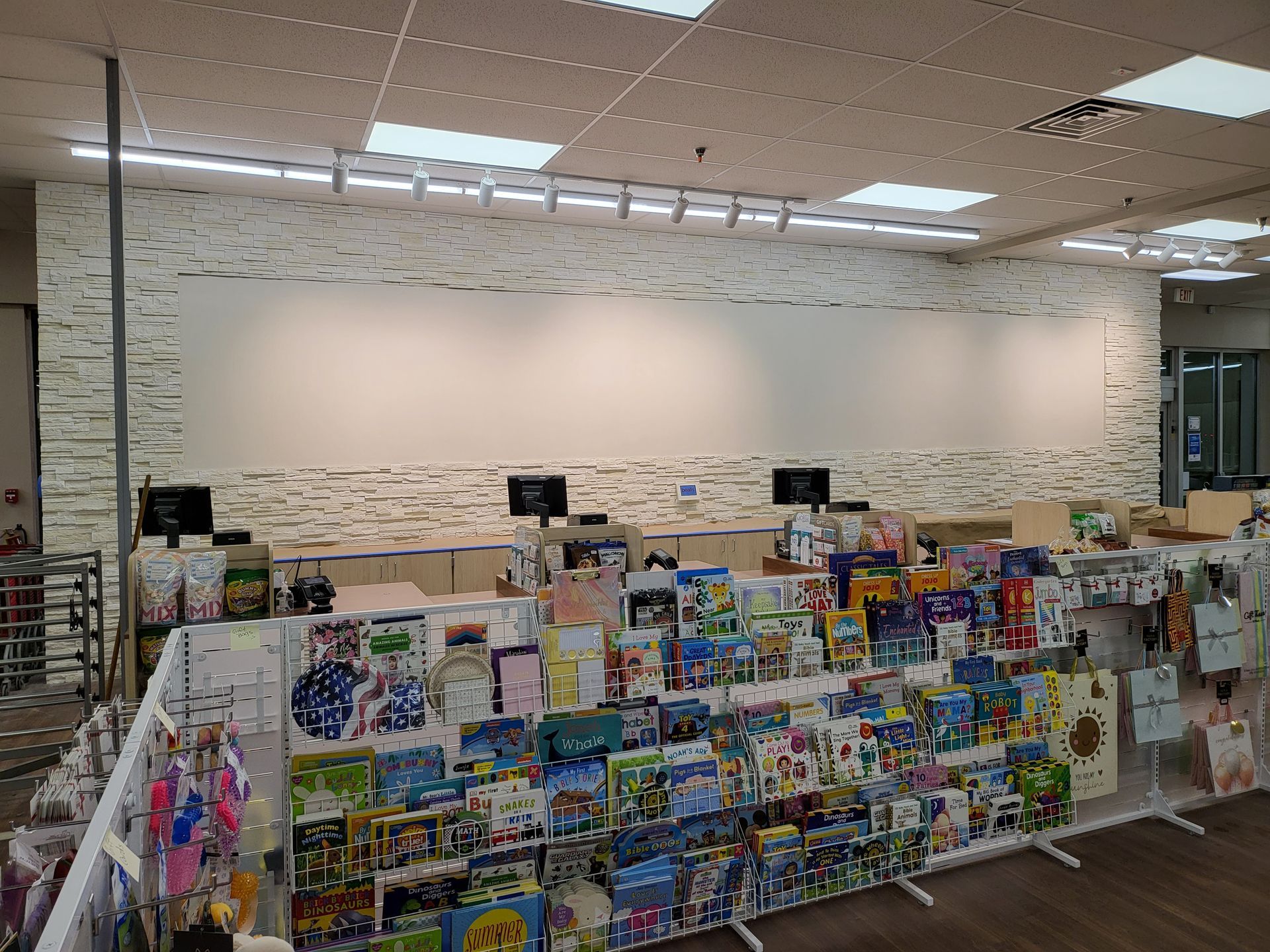 Greeting card and gift display in a bright store aisle with shelves of colorful merchandise