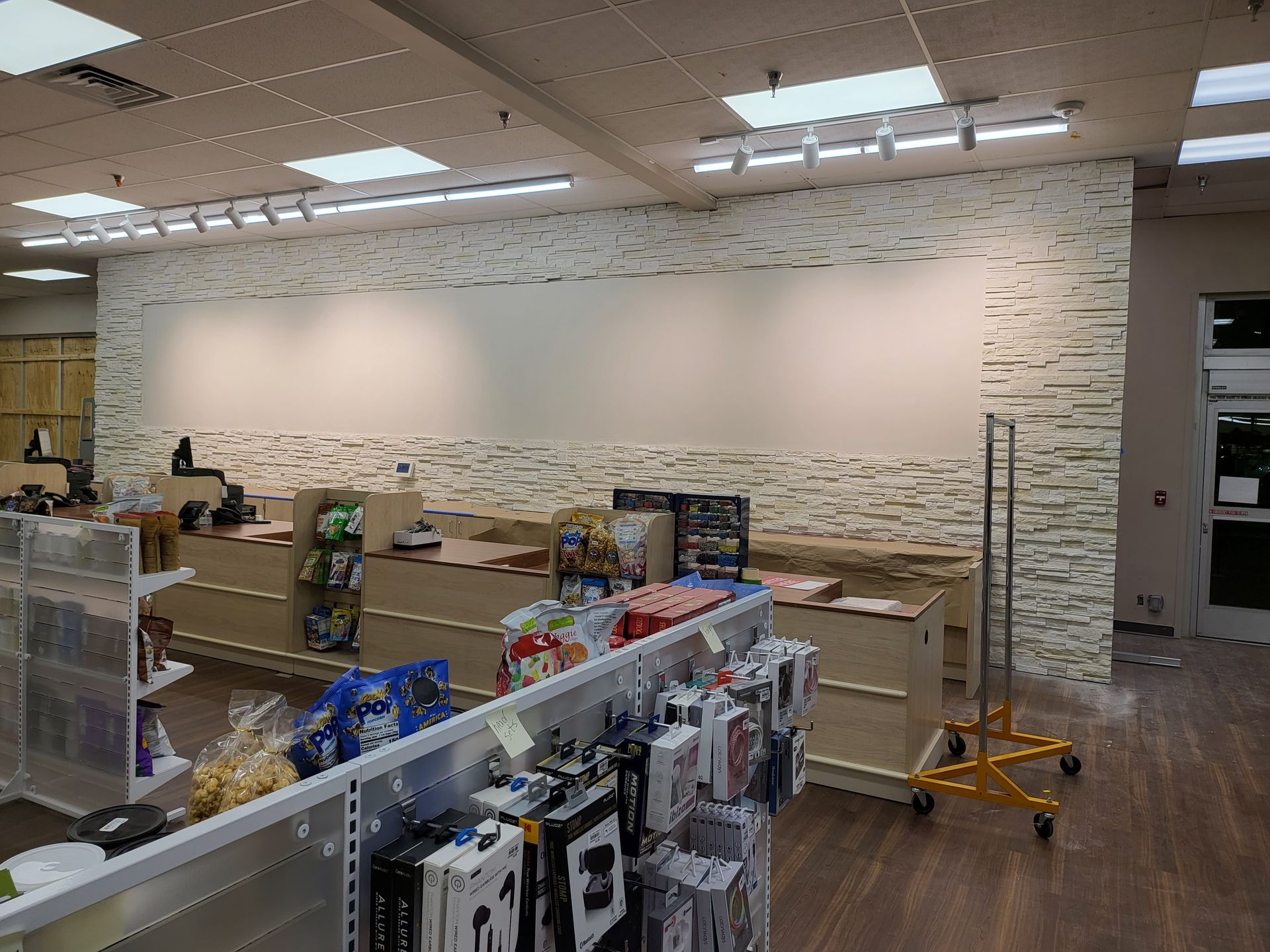 Empty retail store interior with shelves, boxes, and a large blank wall being prepared for renovation