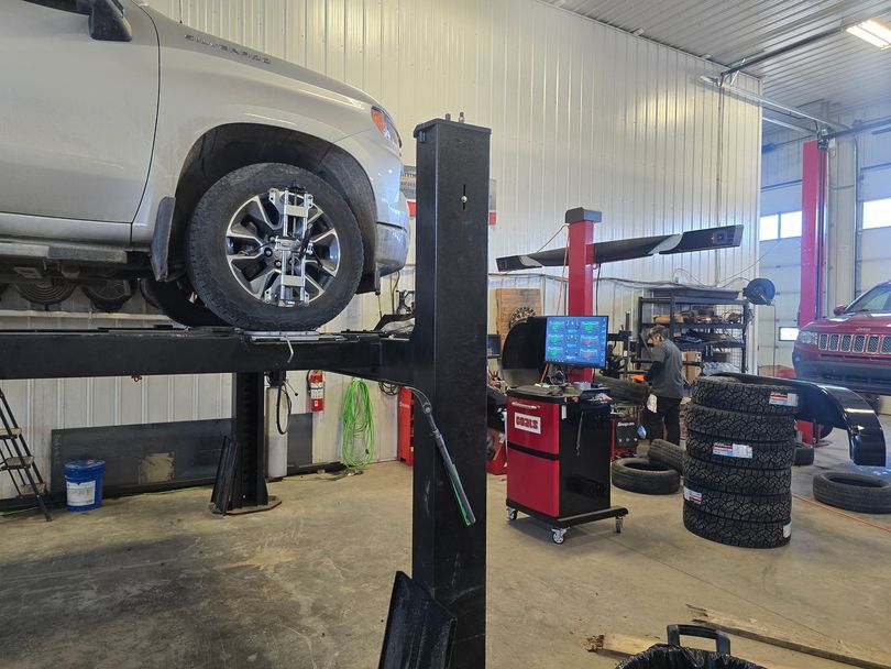 Technician inspecting suspension components on hoist