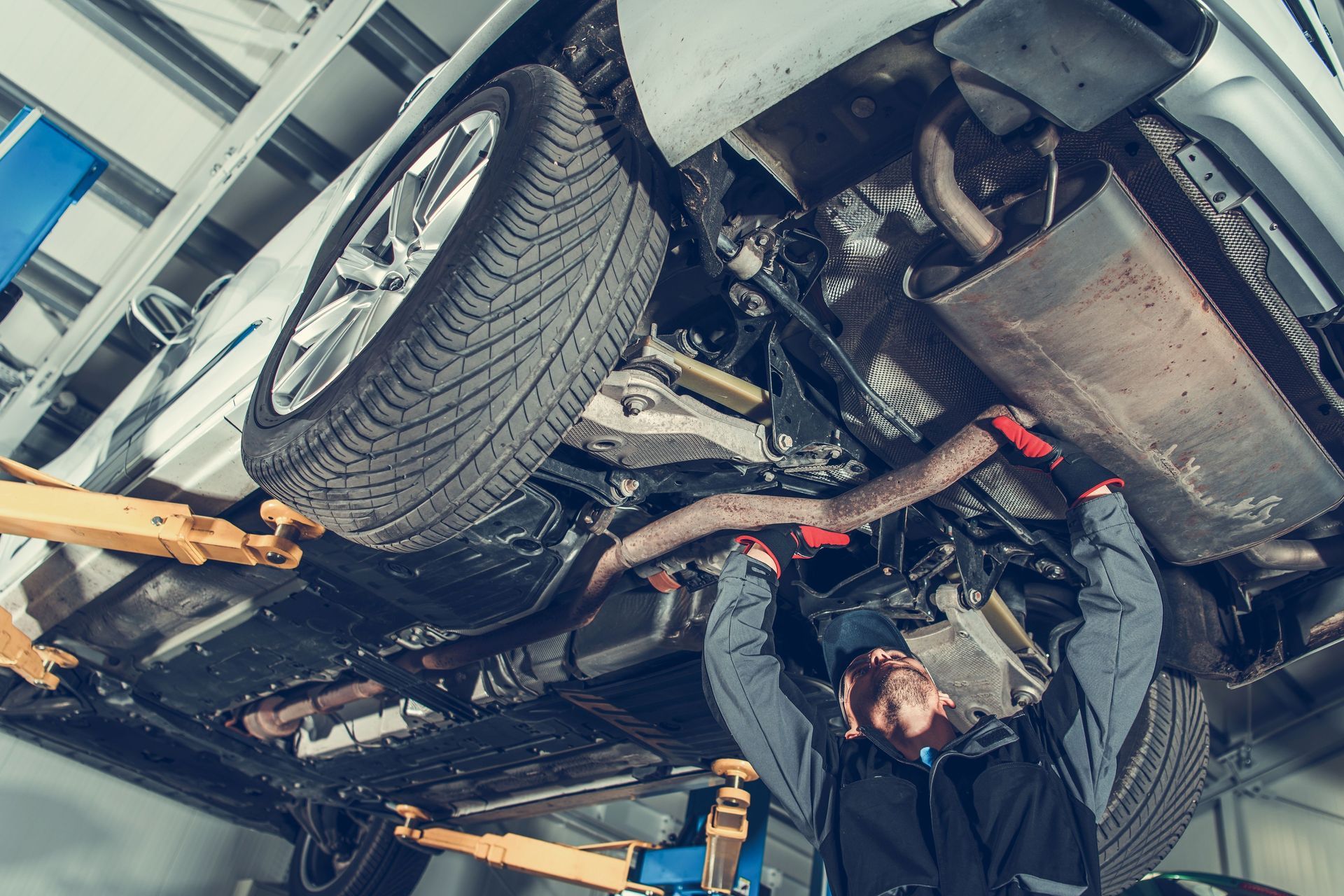 A mechanic repairing an automobile in a workshop. A mechanic repairing an automobile in a workshop.