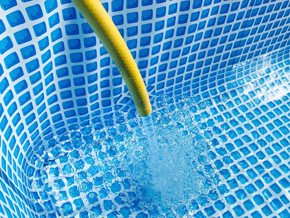 Yellow Hose Spraying Water Into a Blue Pool — Water Top Ups Gympie in Jones Hill, QLD
