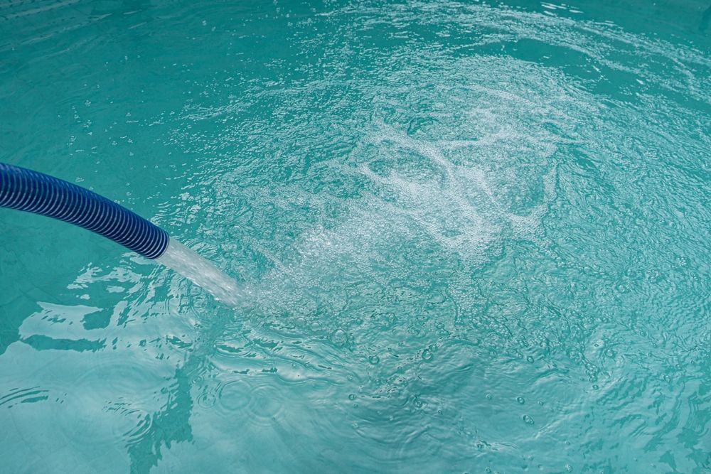 Blue Pool Hose Spraying Water Into Turquoise Pool — Water Top Ups Gympie in Kybong, QLD