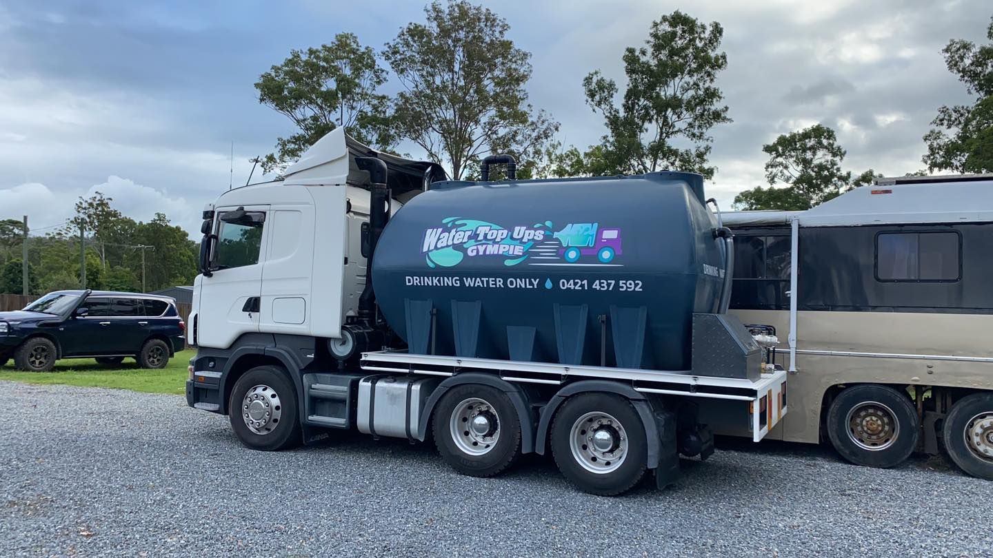 Semi-truck With a Large Black Water Tank Attached to a Trailer — Water TopUps Gympie in Pie Tamaree, QLD