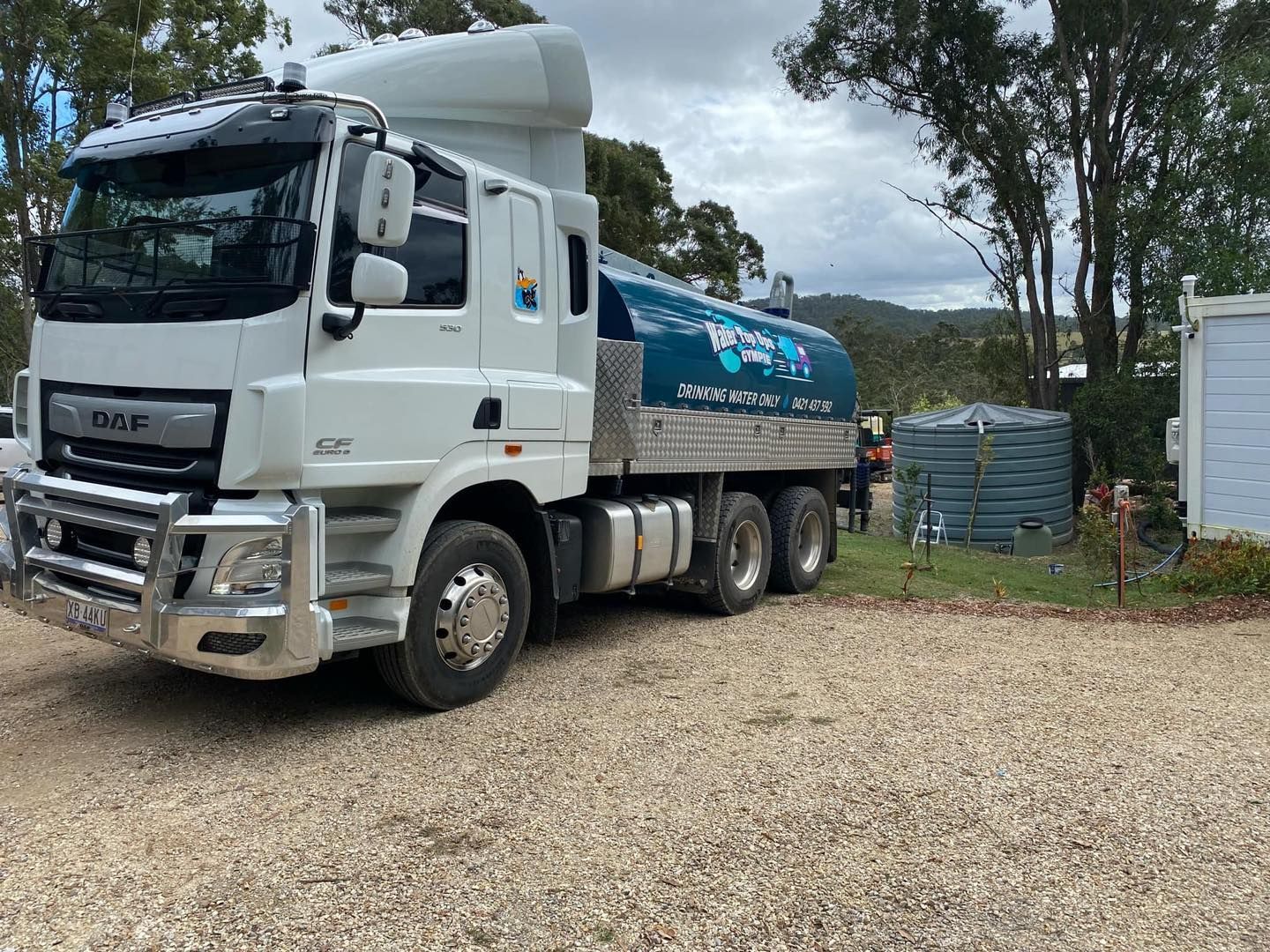 White Tanker Truck Parked on Gravel, Beside a Water Tank — Water TopUps Gympie in Curra, QLD