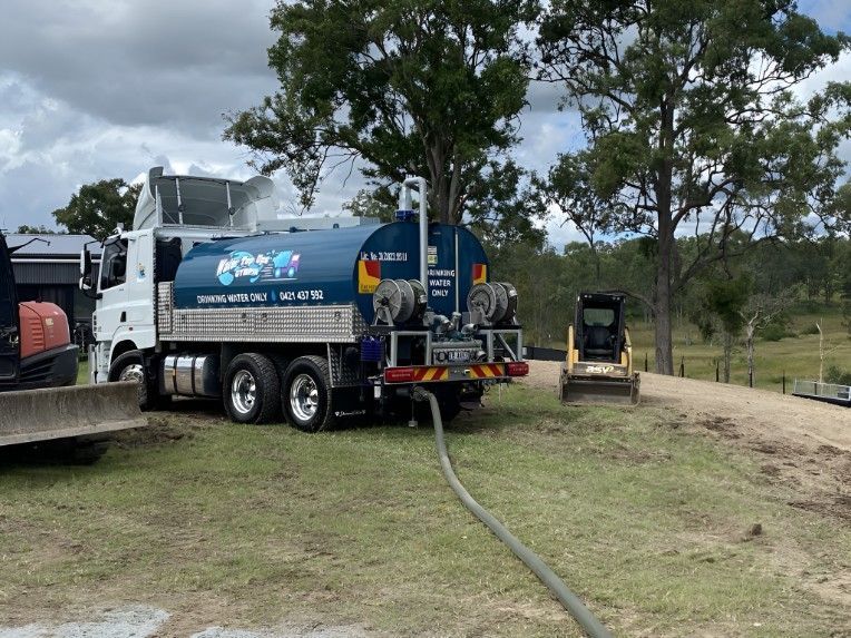 A Blue Truck With a Hose Attached to It is Parked in a Field — Water TopUps Gympie in Curra, QLD