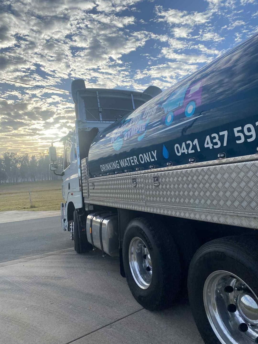 A blue water tanker truck parked on concrete with a cloudy sky background — Water TopUps Gympie in Araluen, QLD