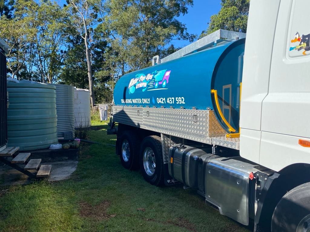 Blue and White Vacuum Truck Parked on Grass Beside a Building and Trees — Water Top Ups Gympie in Chatsworth, QLD