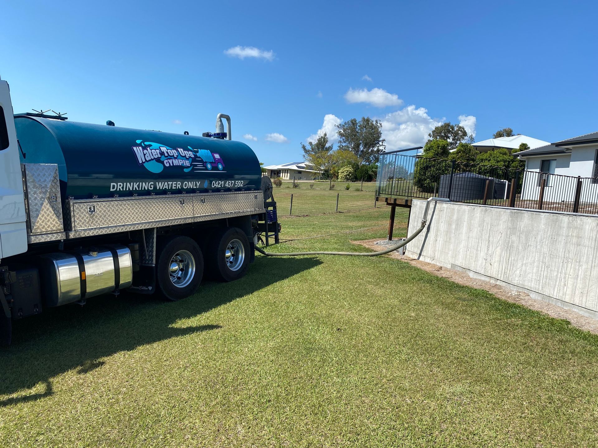Blue Water Tanker Truck Parked on Grass Beside a Fence — Water Top Ups Gympie in Curra, QLD