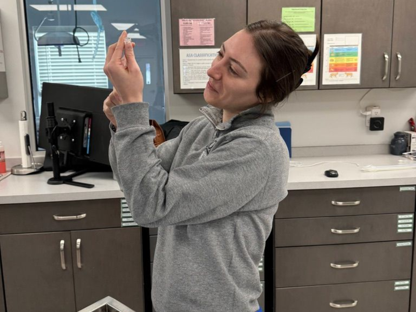 A vet holding a tabby kitten, with an ear medicine bottle on the table.