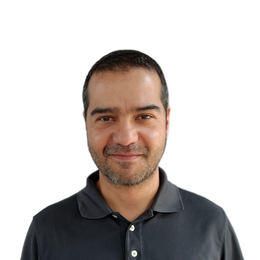 Retrato de estudio de un hombre sonriente con una camisa polo oscura sobre un fondo blanco.
