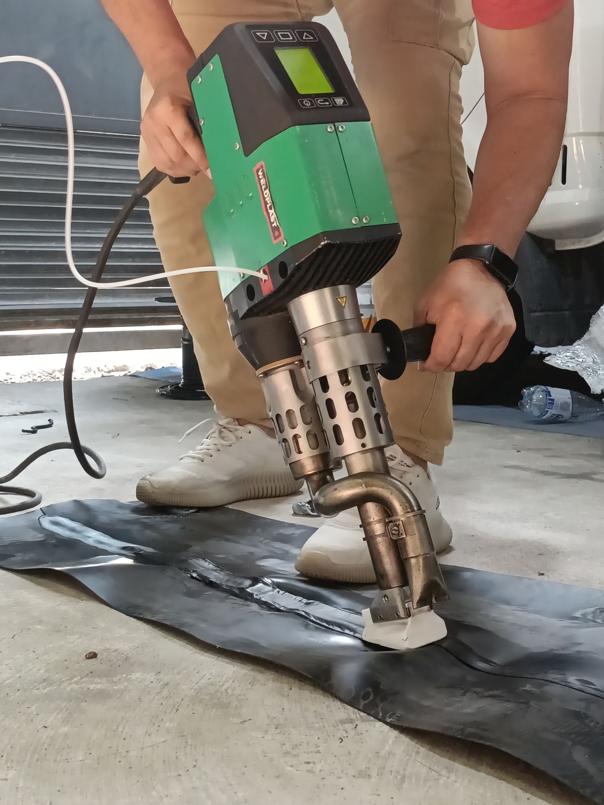 Trabajador utilizando una pulidora de suelos verde sobre una superficie de hormigón en el interior.