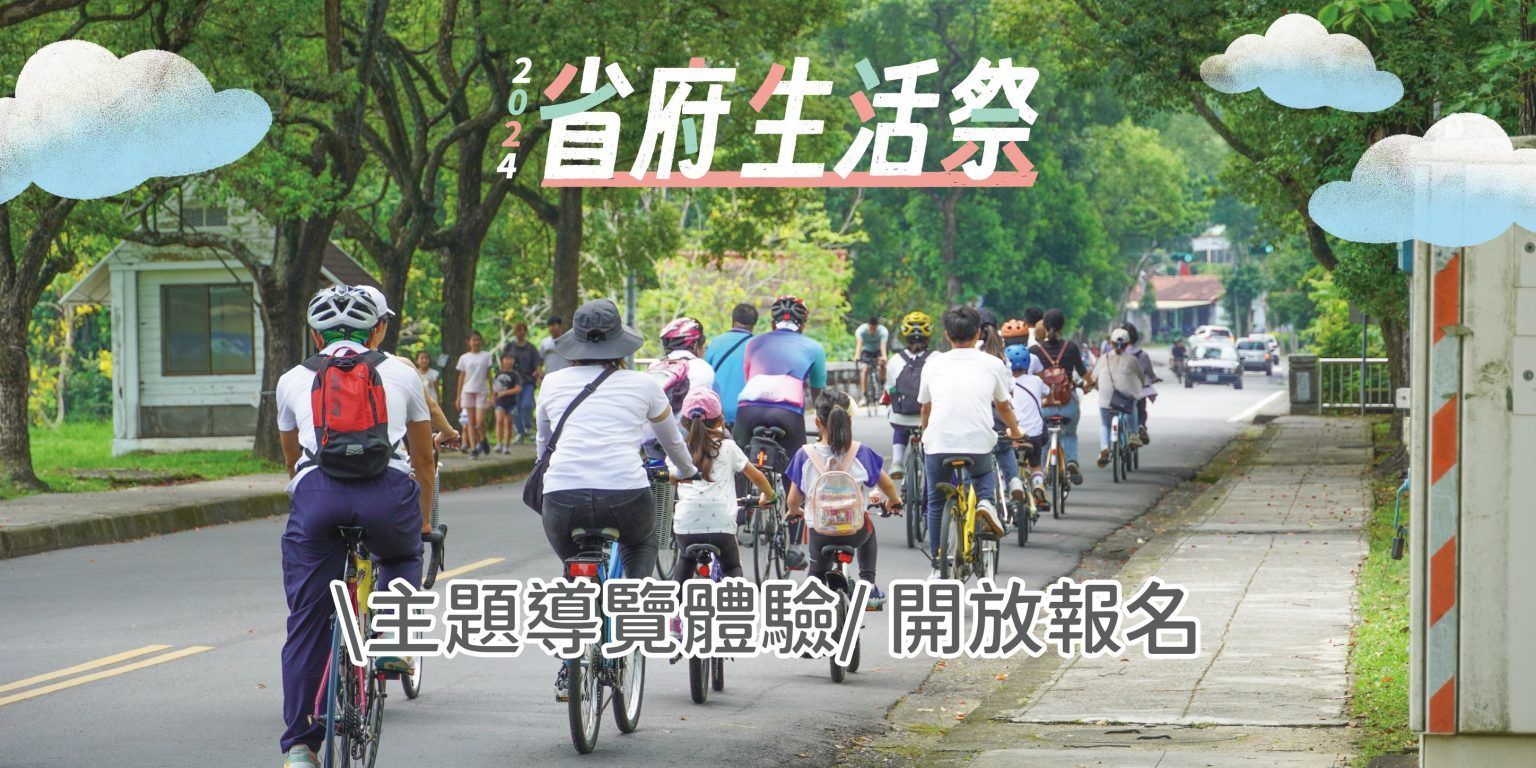 人們騎著腳踏車、走在綠樹成蔭的道路上，上方掛著寫有「首府生活祭」的布條。