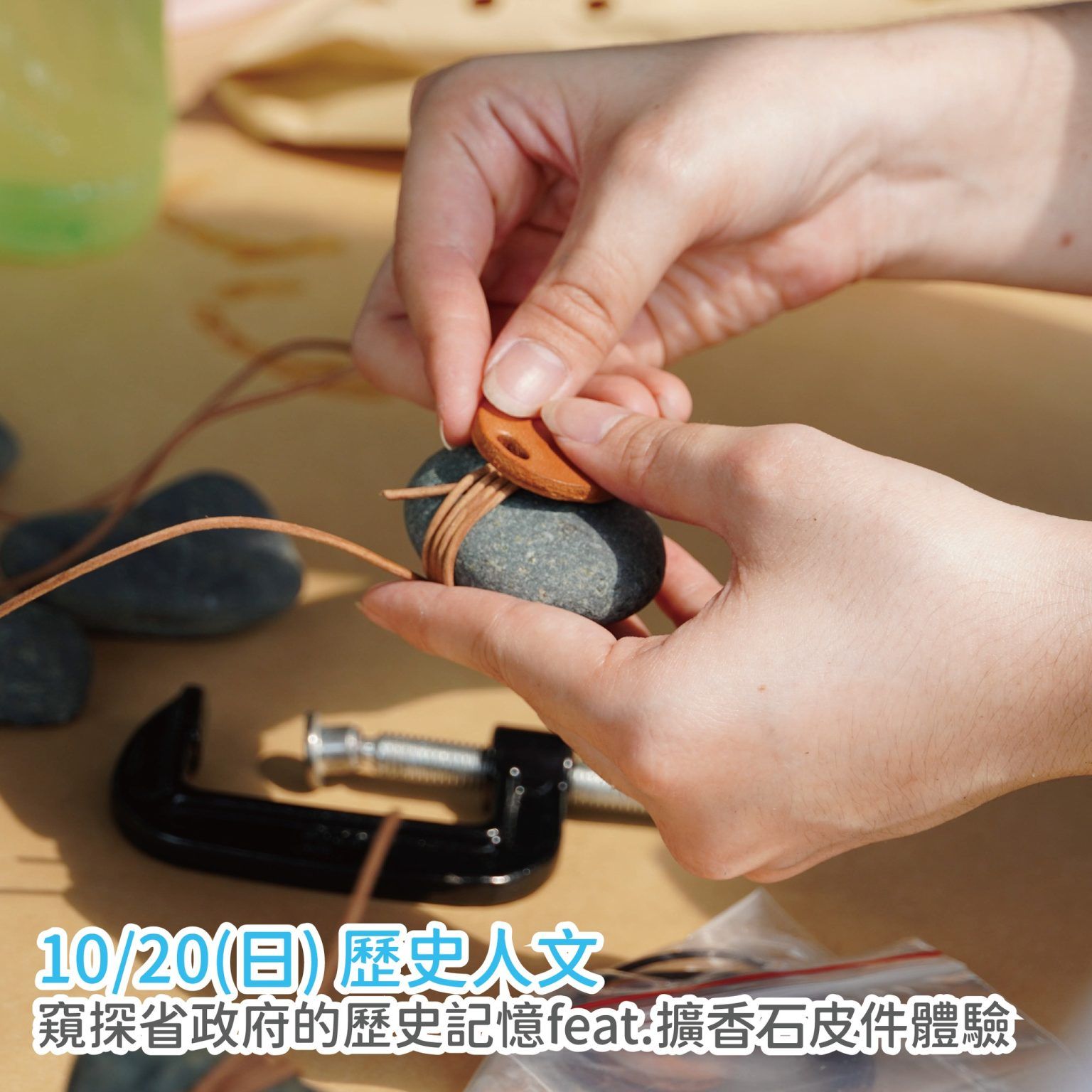 雙手在桌子上用夾鉗和工具塑造一個橙灰色的小石工藝品。