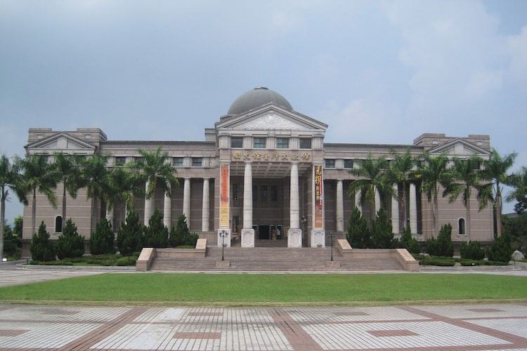 宏偉的新古典主義建築,圓頂和立柱,棕櫚樹環繞,寬闊的草坪,陰雲密佈的天空下。