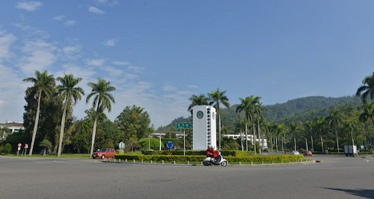 寬闊的公園廣場,棕櫚樹成蔭,一座白色紀念碑矗立其間,遠處是連綿起伏的山丘,頭頂是湛藍的天空。