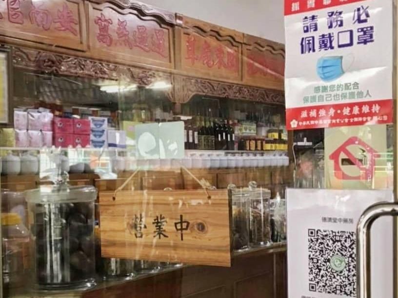 店面設有玻璃展示櫃、中文招牌，門上貼著「暫停營業」的告示。