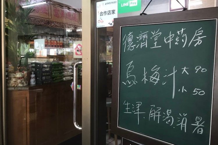 中餐館門口，玻璃門旁掛著一塊用白色字跡寫的黑板菜單。