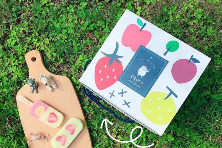 草地上擺放著兒童美術用品、水果主題卡和木製砧板。