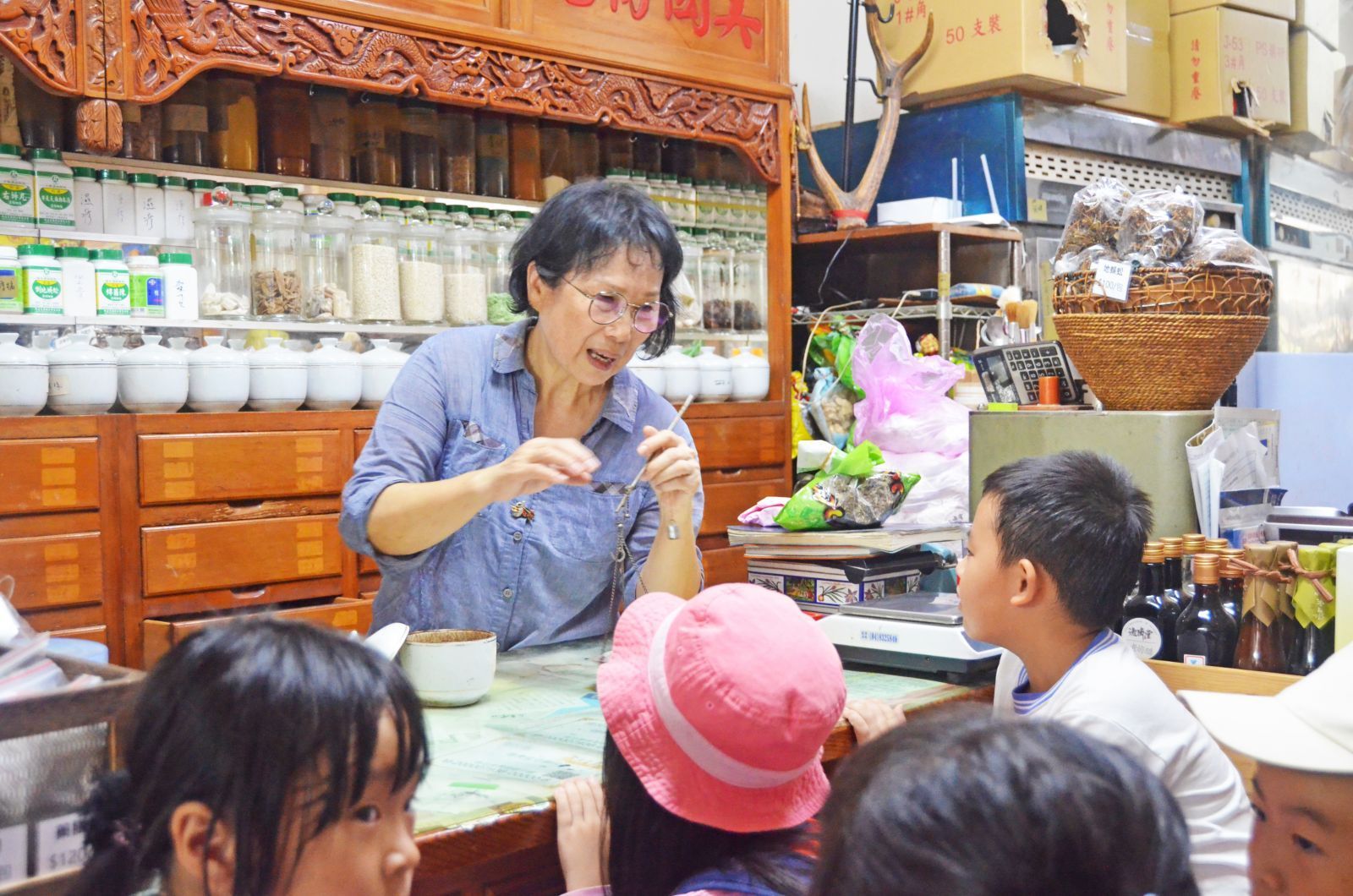 攤販在擺放著罐子和鮮花的市場攤位上與孩子們交談