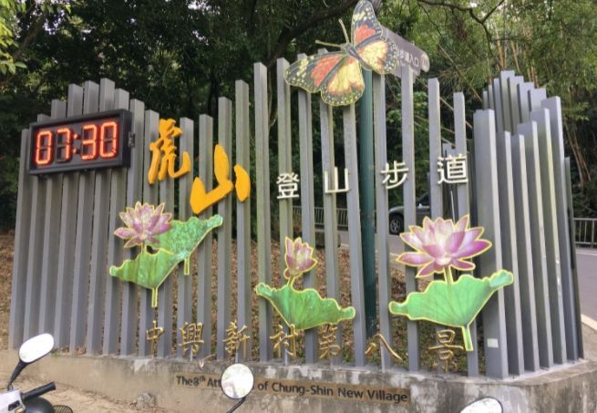 裝飾步道指示牌，飾有漢字、蝴蝶和蓮花圖案，以及顯示時間為 07:30 的數位時間顯示器。