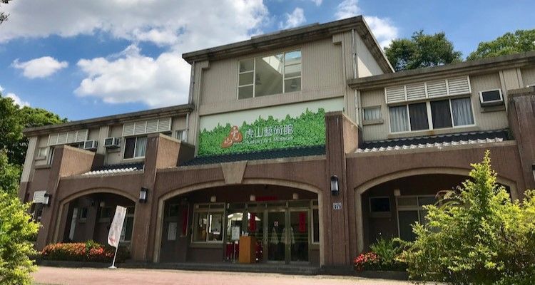 在陰雲密佈的天空下,一棟磚造建築的正門入口處掛著綠色招牌,拱形雨篷遮蔽著天空。