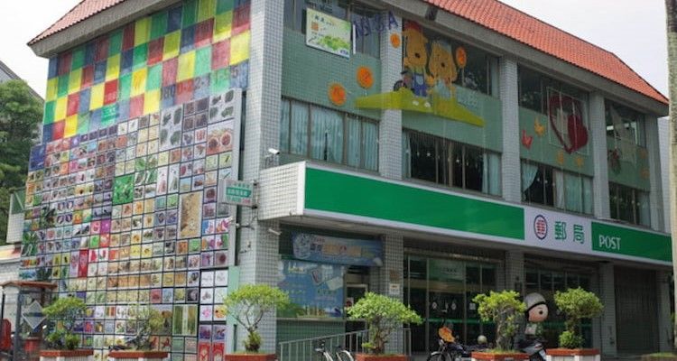 一棟色彩鮮豔的兩層店面,外牆繪有瓷磚壁畫,入口上方掛著綠色招牌。