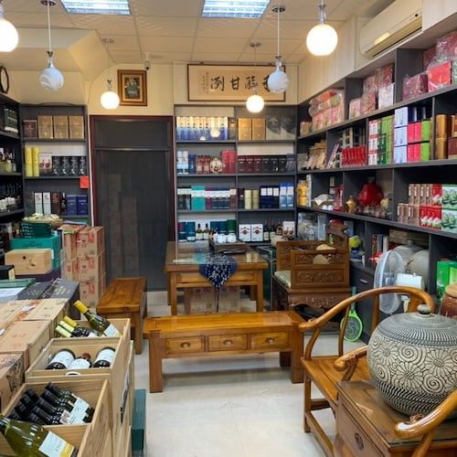 小茶館內部，木桌、擺滿彩色茶葉盒的架子和懸掛的燈具。