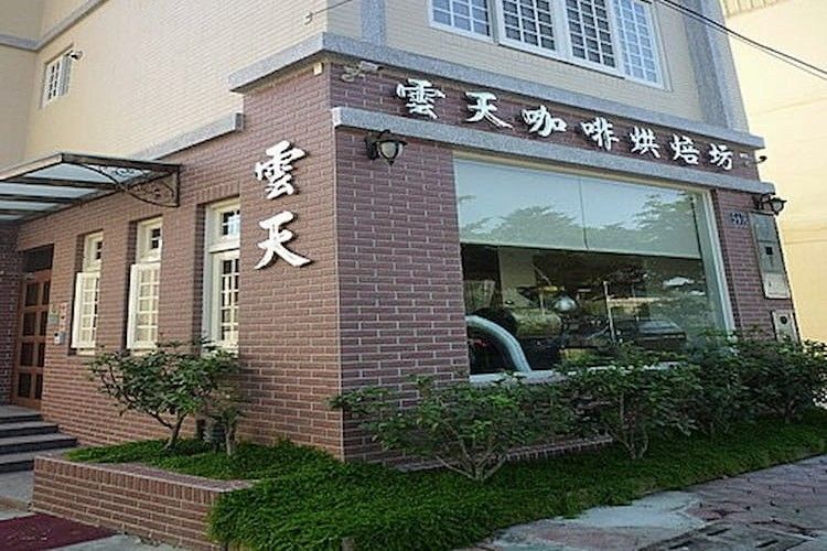 磚砌店面，配有大型中文招牌和玻璃窗，旁邊是一小片綠色樹籬。