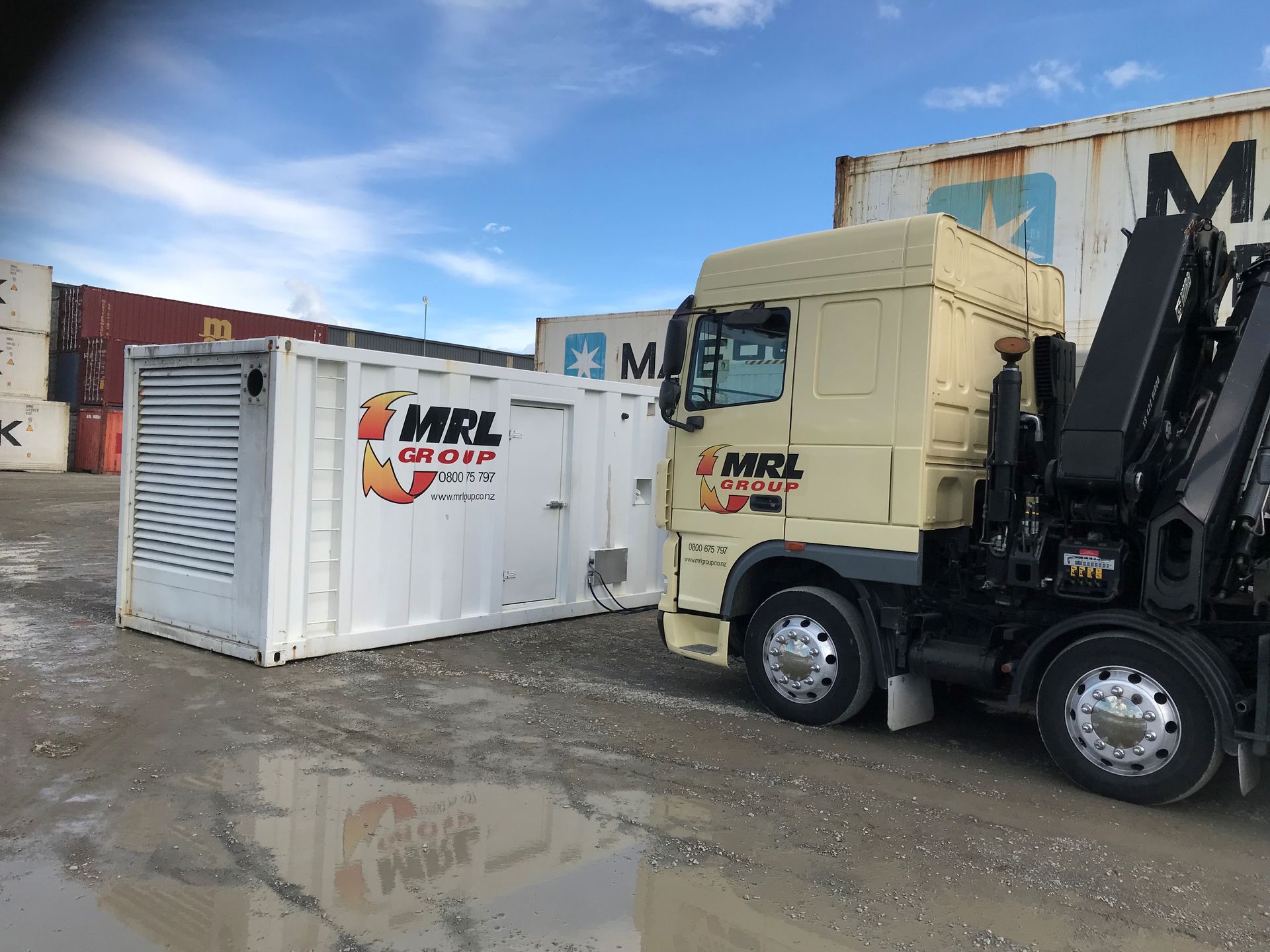A truck is parked next to a container in a parking lot.