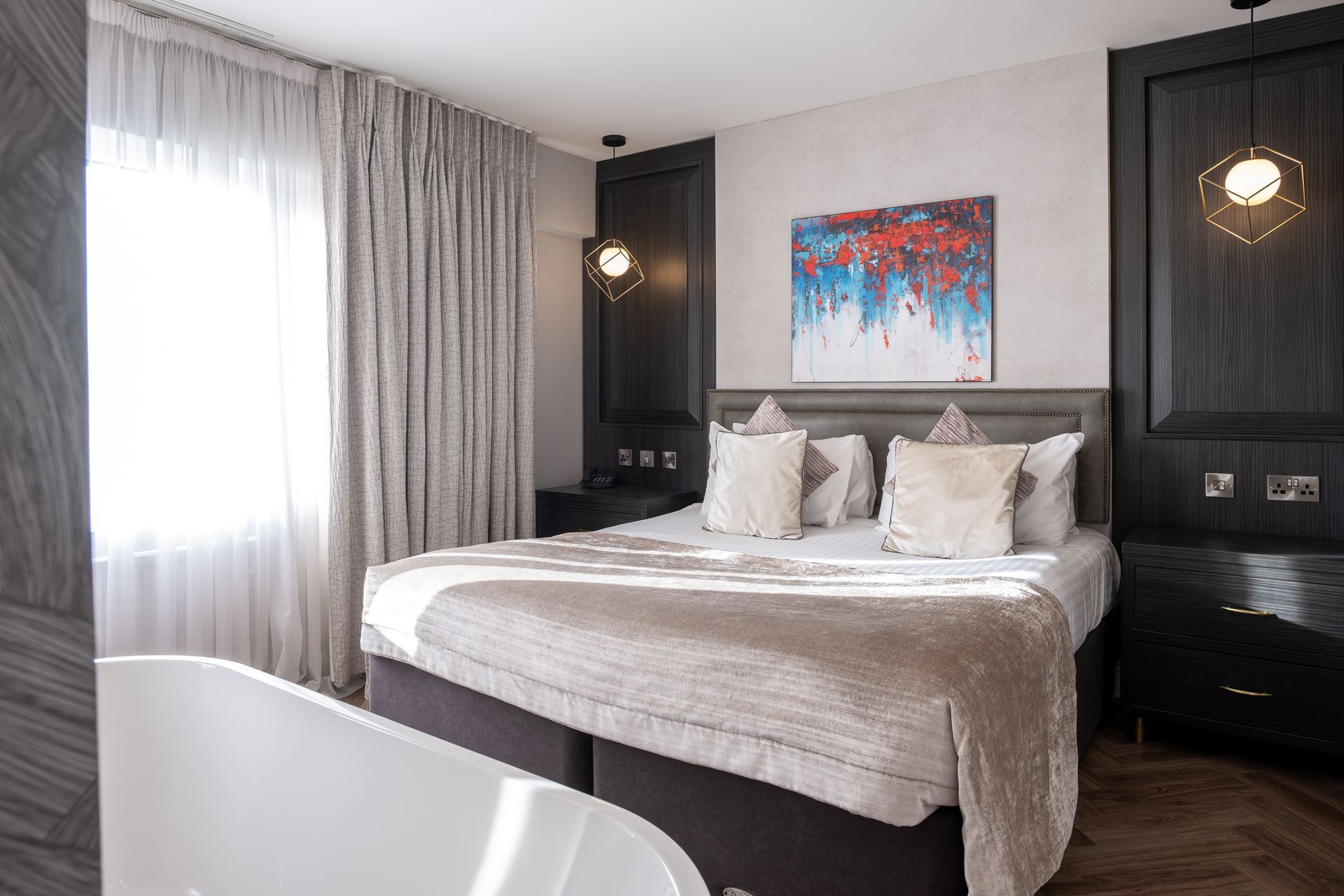 Modern bedroom with a large bed, floor-to-ceiling curtains, and dark wood accent walls