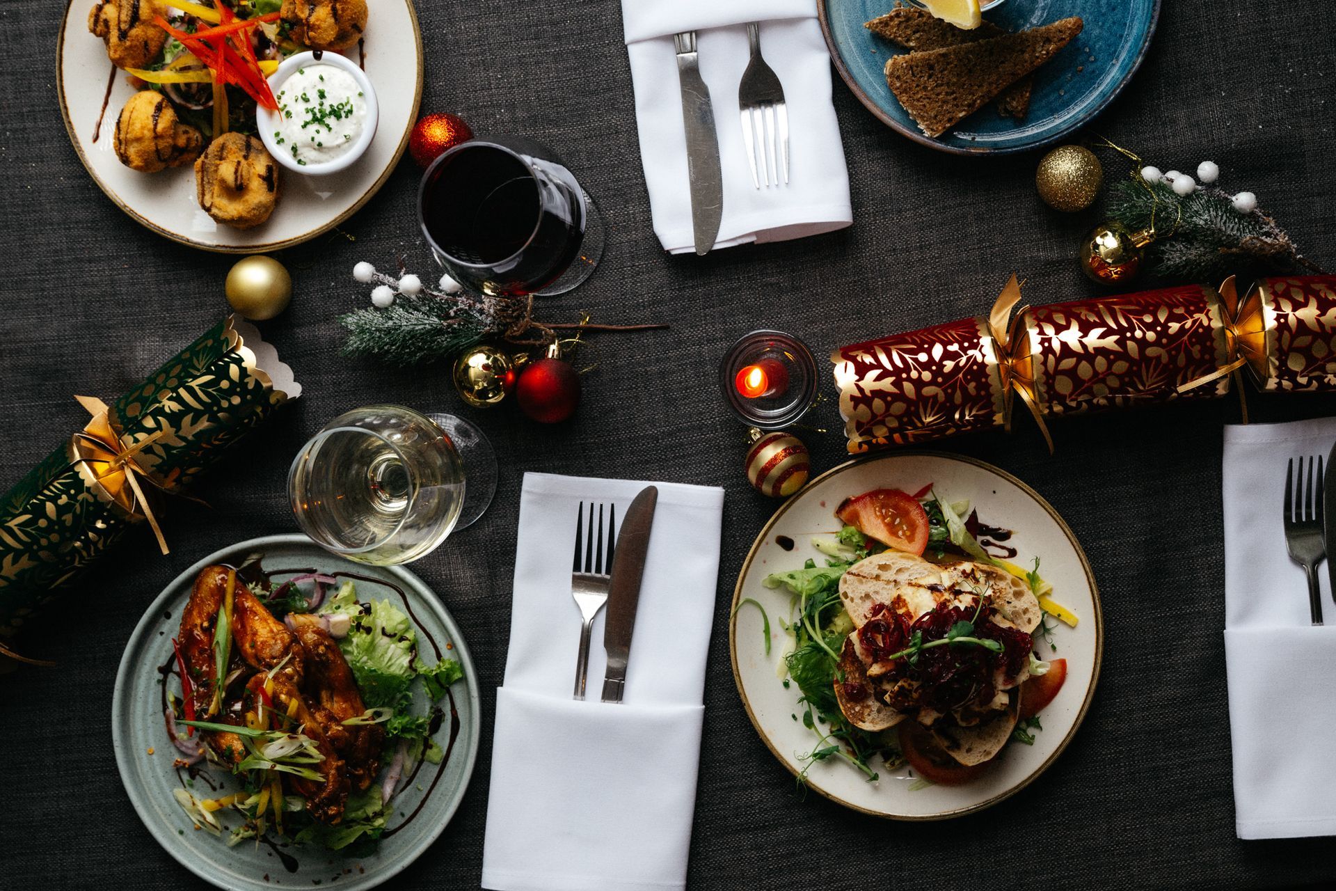 Festive dinner table with plated meals, wine glasses, candles, and holiday decorations