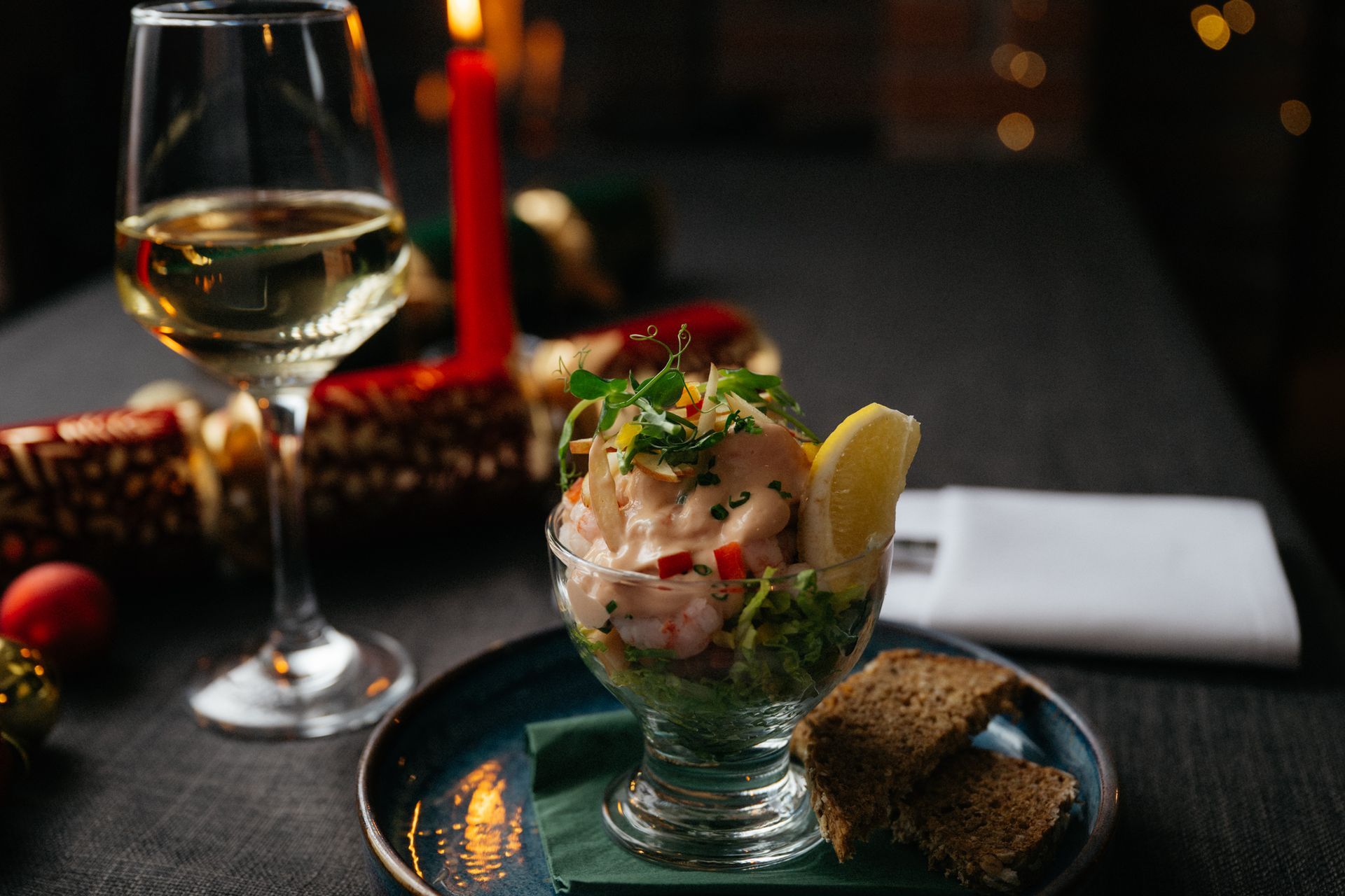 Gourmet seafood appetizer and white wine on a dimly lit table with a candlelit, elegant setting