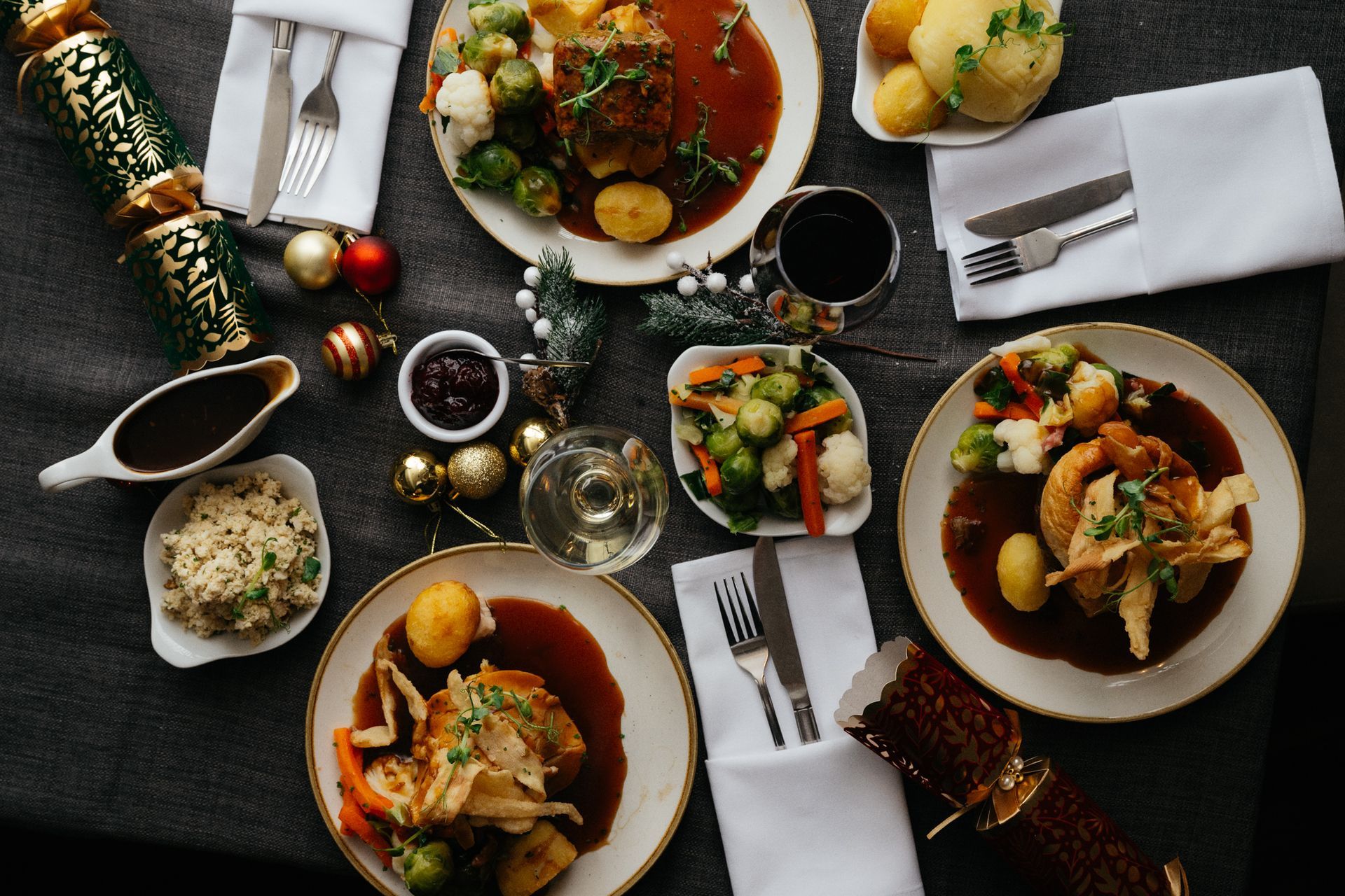 Top-down view of a gourmet dinner table with plated dishes, wine, candles, and folded napkins