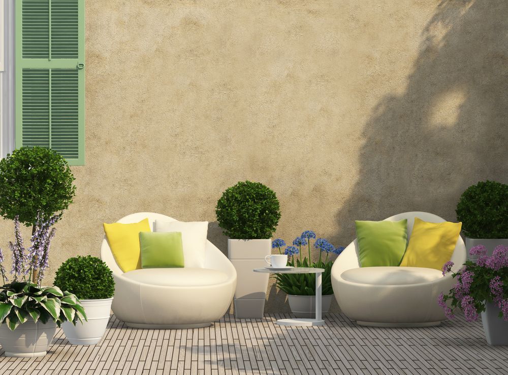 Outdoor Patio With White Chairs, Green Pillows, Potted Plants — Precision Fencing & Landscaping in Thurgoona, NSW