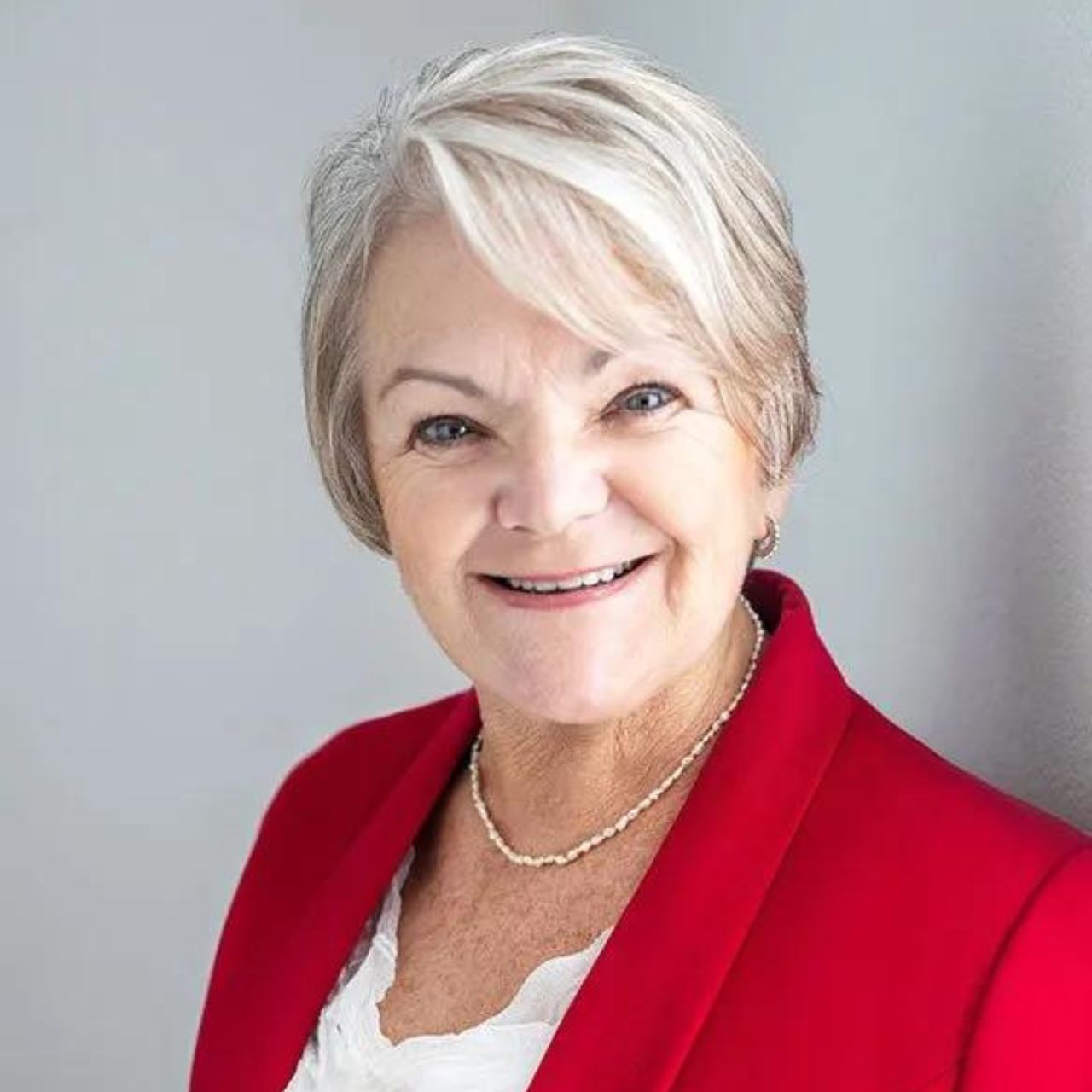 Jan Sky from Brain Potential - a woman wearing a red jacket and a necklace is smiling for the camera .