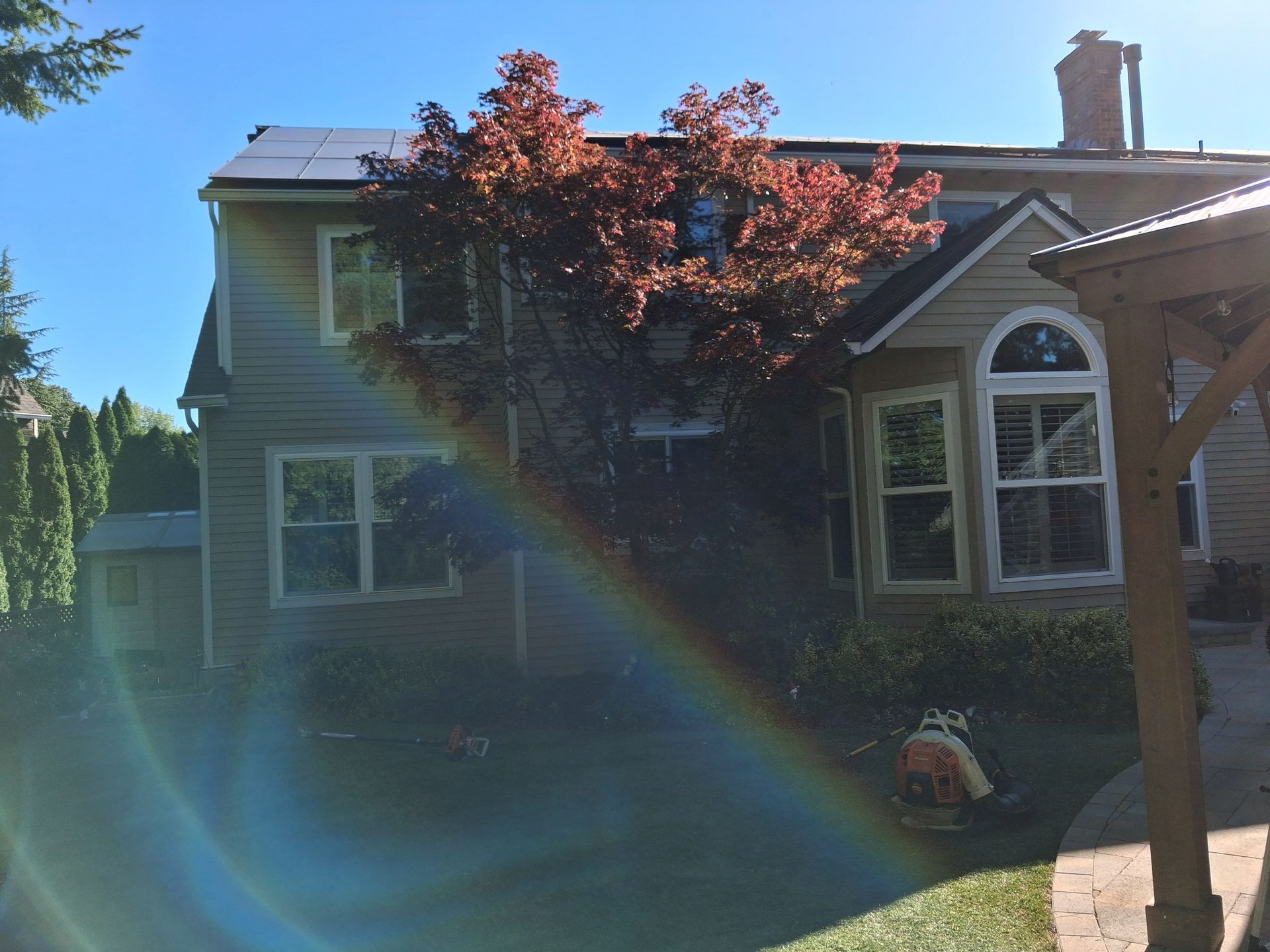 House with rainbow lens flare in a sunny yard
