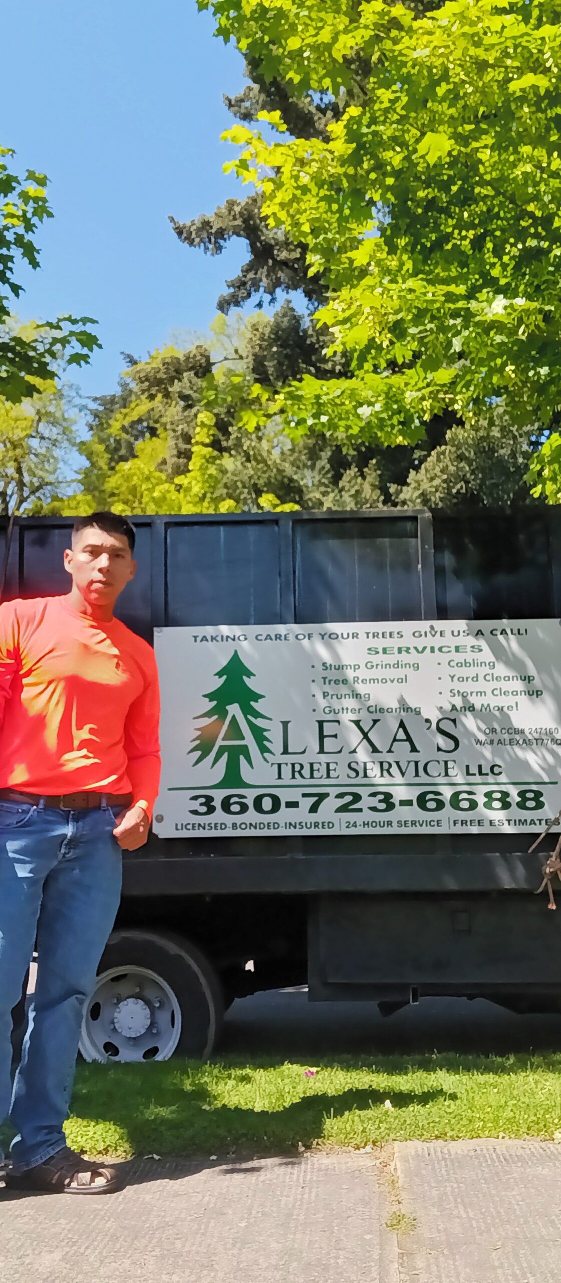 Man standing beside a Texas Tree Service trailer under bright green trees