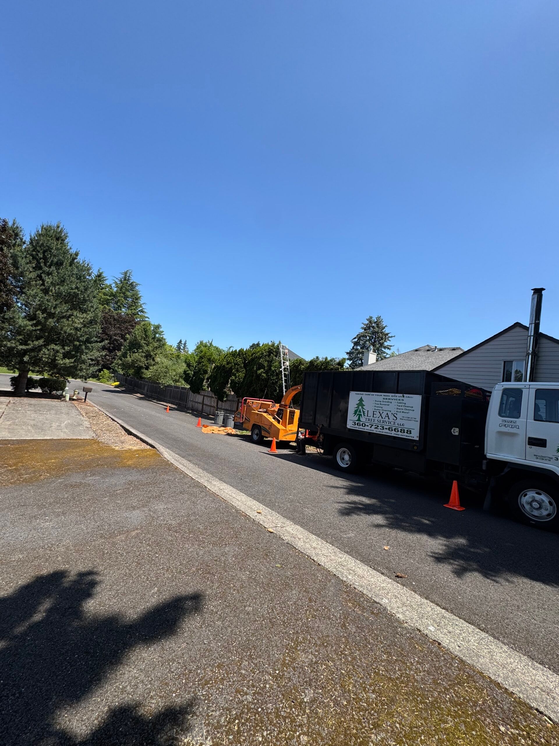 Roadside work zone with orange machinery and a white dump truck under a clear blue sky