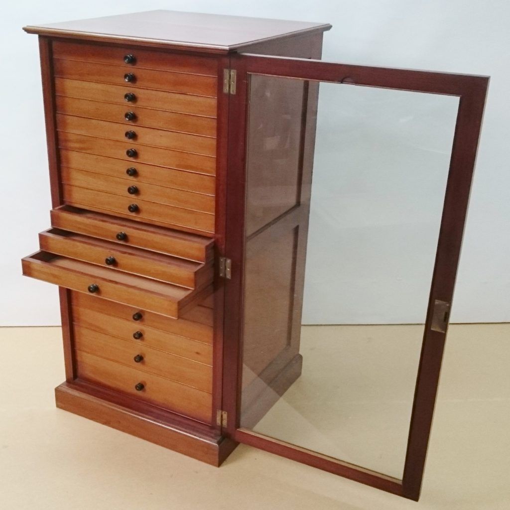 A wooden cabinet with drawers and a glass door