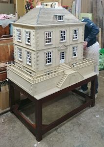 A man is standing next to a model of a house on a table
