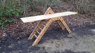 A wooden bench is sitting on the ground in the woods.