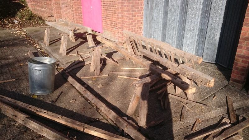 A pile of wood is sitting on the ground next to a metal bucket.